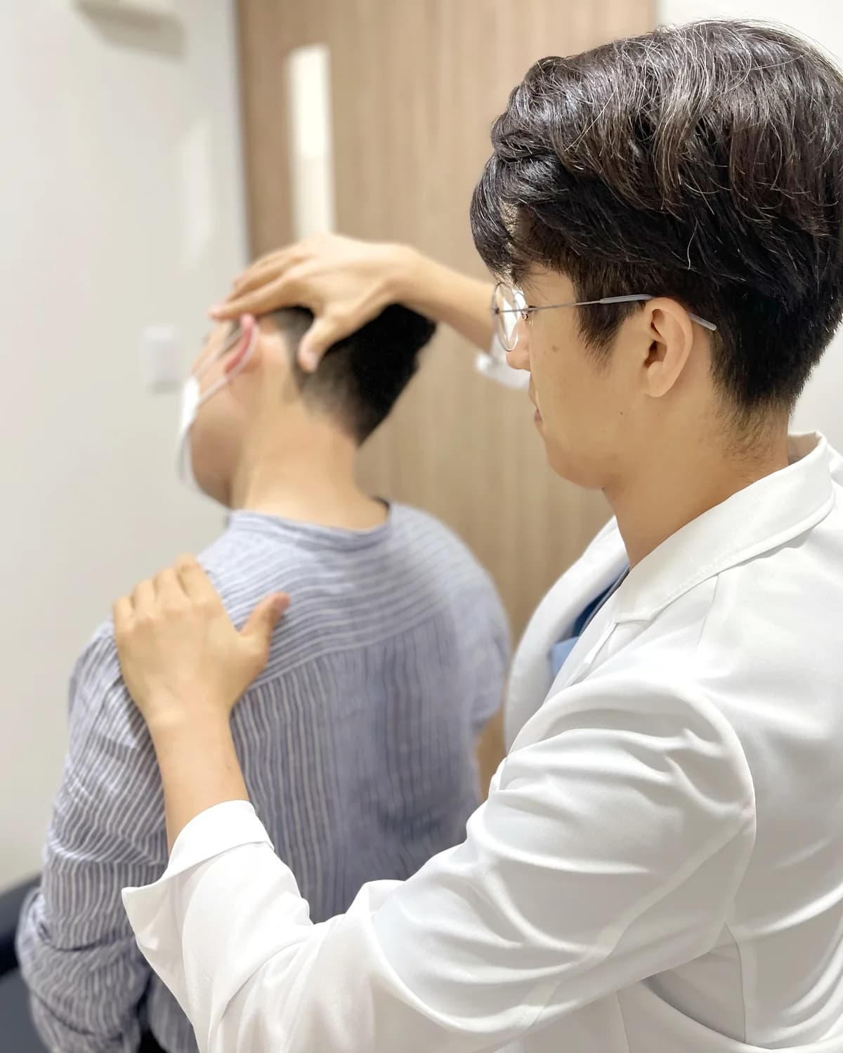 환자의 목과 뒷머리를 촉진하며 진료하는 장면